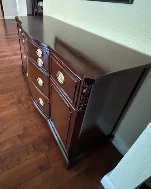 Refinished serpentine dresser with deep cherry finish and brass oval hardware