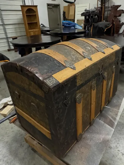 Before and after restoration of an antique steamer trunk with embossed tin and brass hardware - before